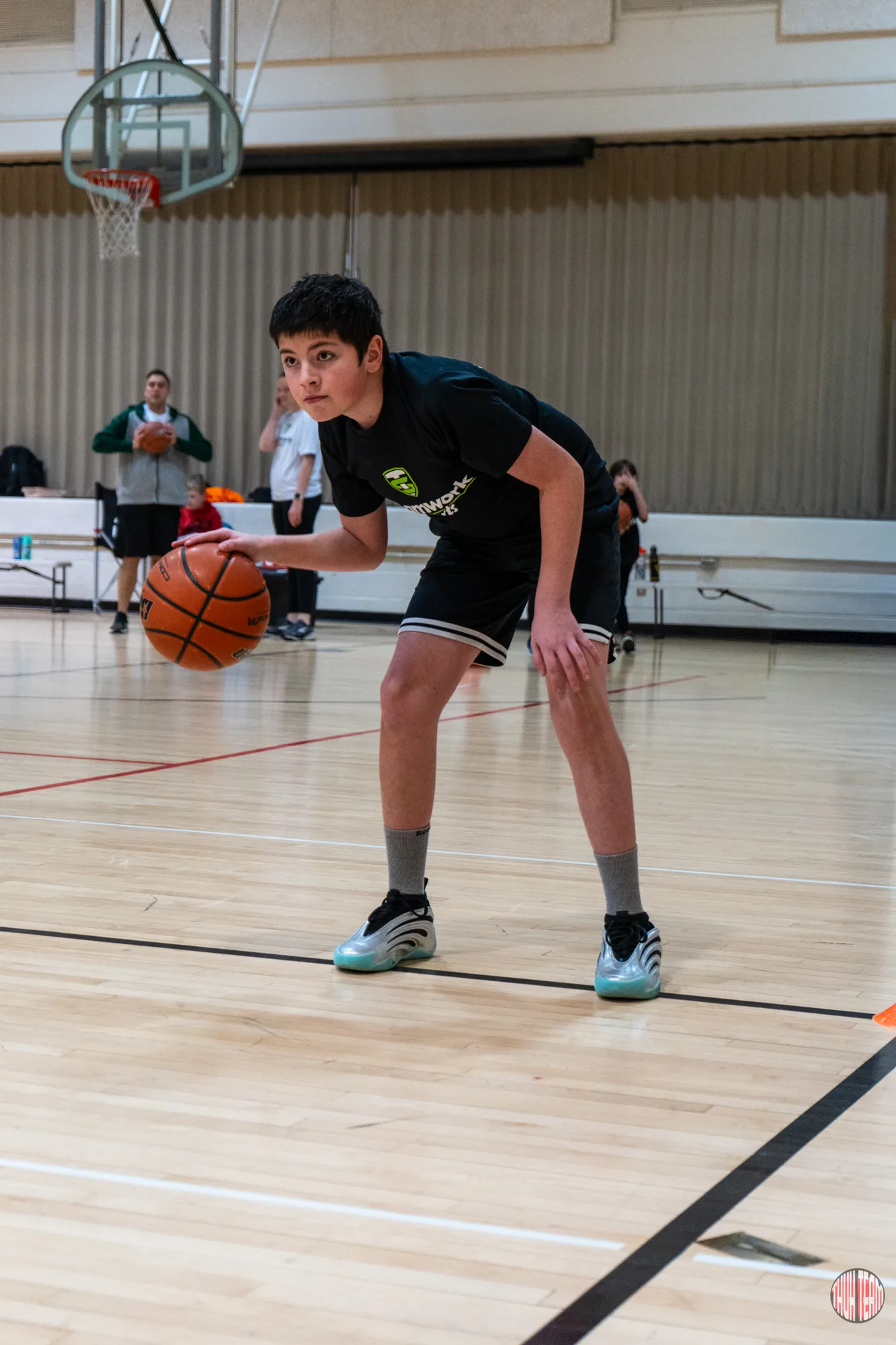 Young basketball player in a Teamwork shirt dribbling low on the gym floor