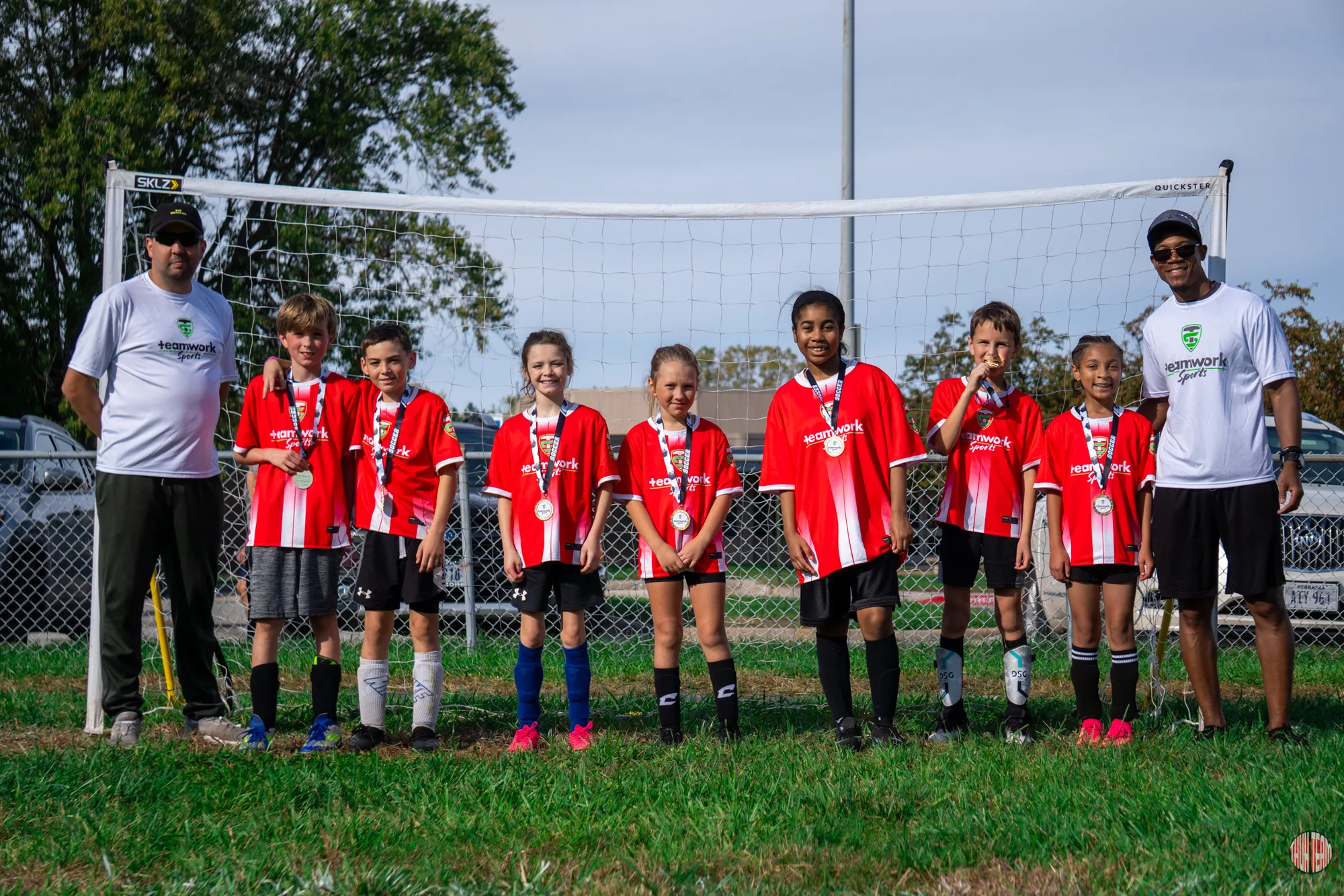 A youth soccer team in red jerseys posing with their coaches