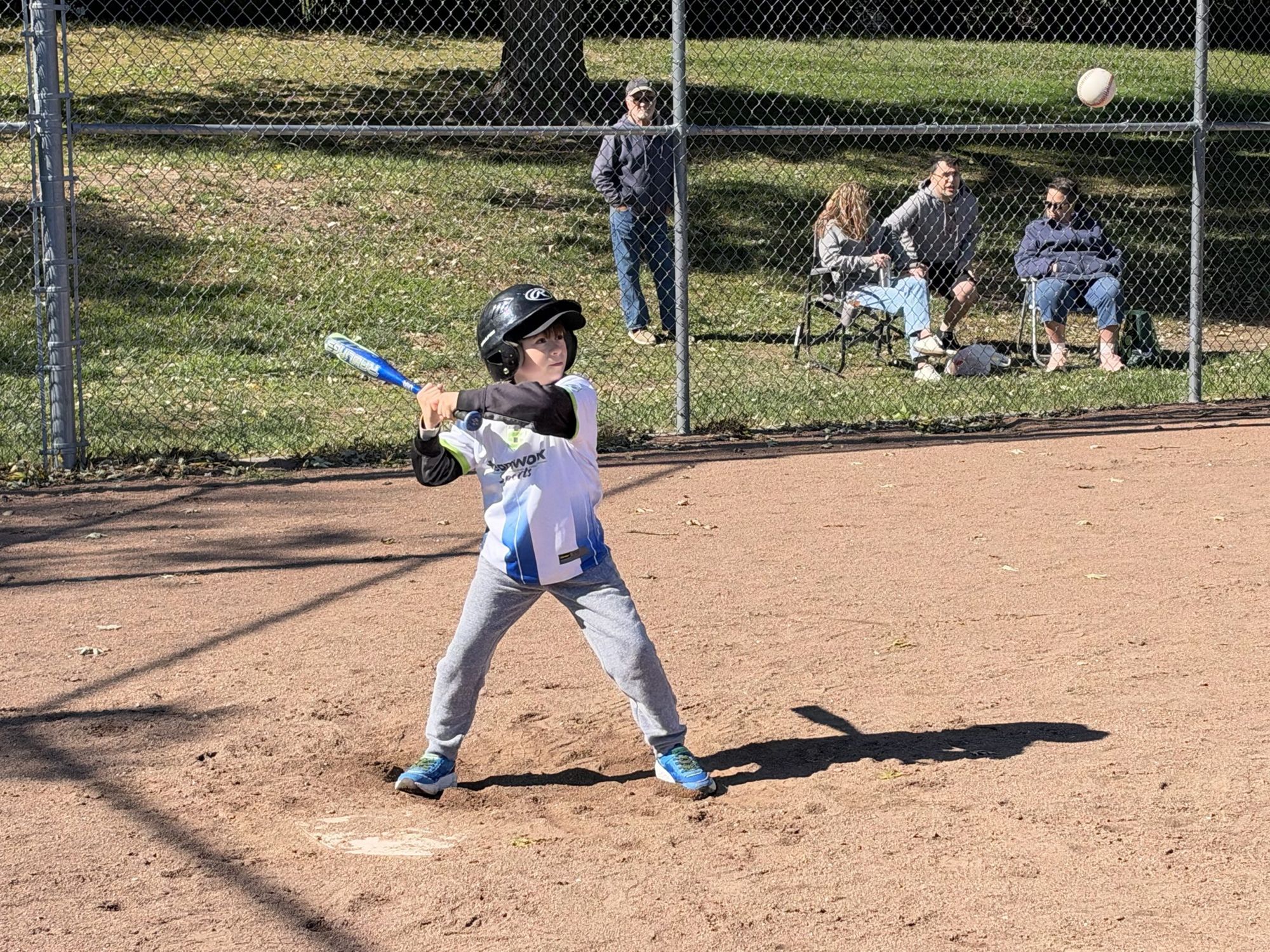 A boy in a Teamwork jersey and batting helmet swinging at a pitch