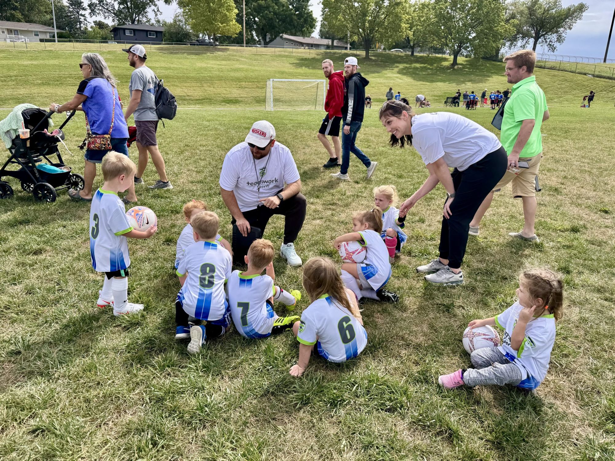 A Teamwork coach smiling with young players on the field