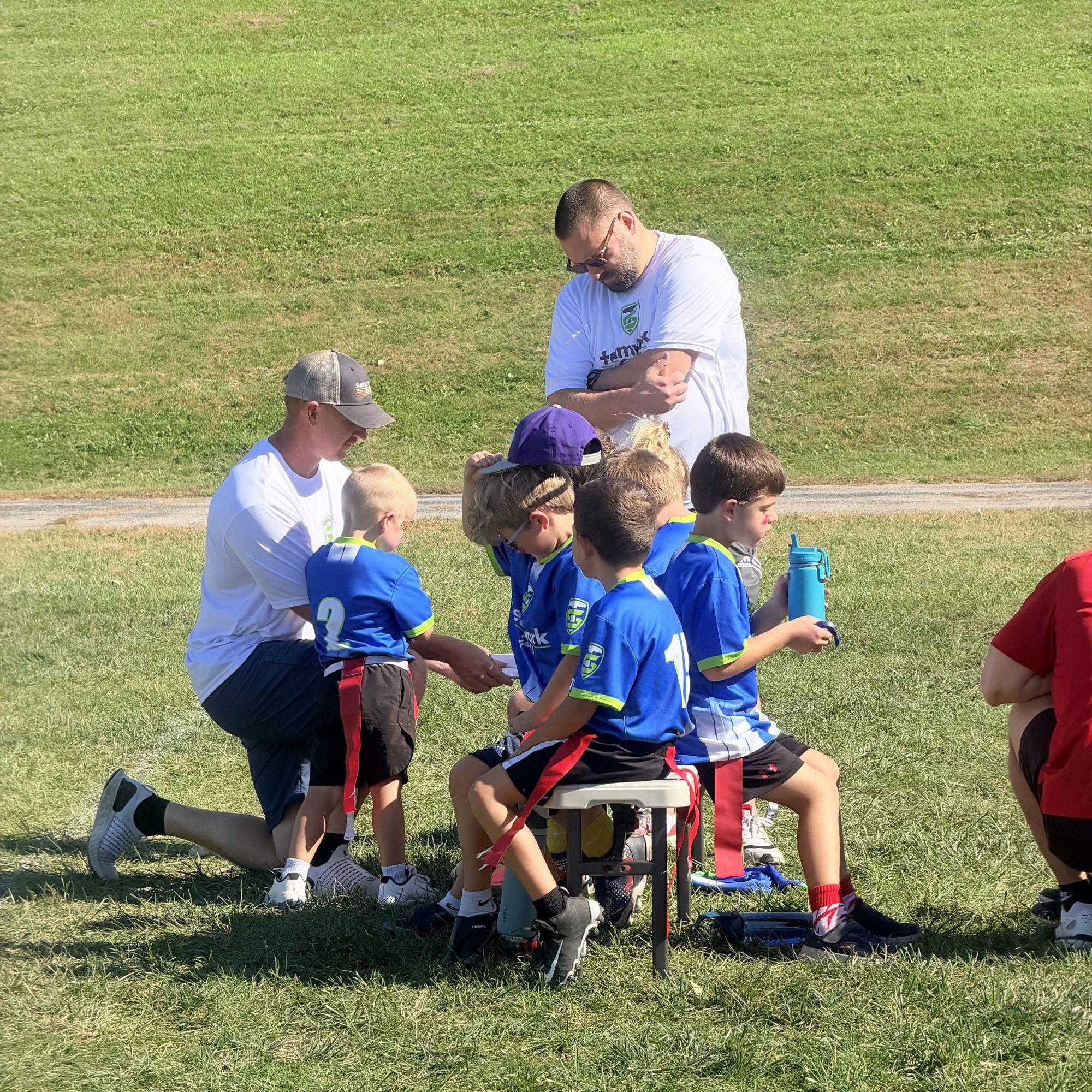 A Teamwork coach kneeling to talk with young players