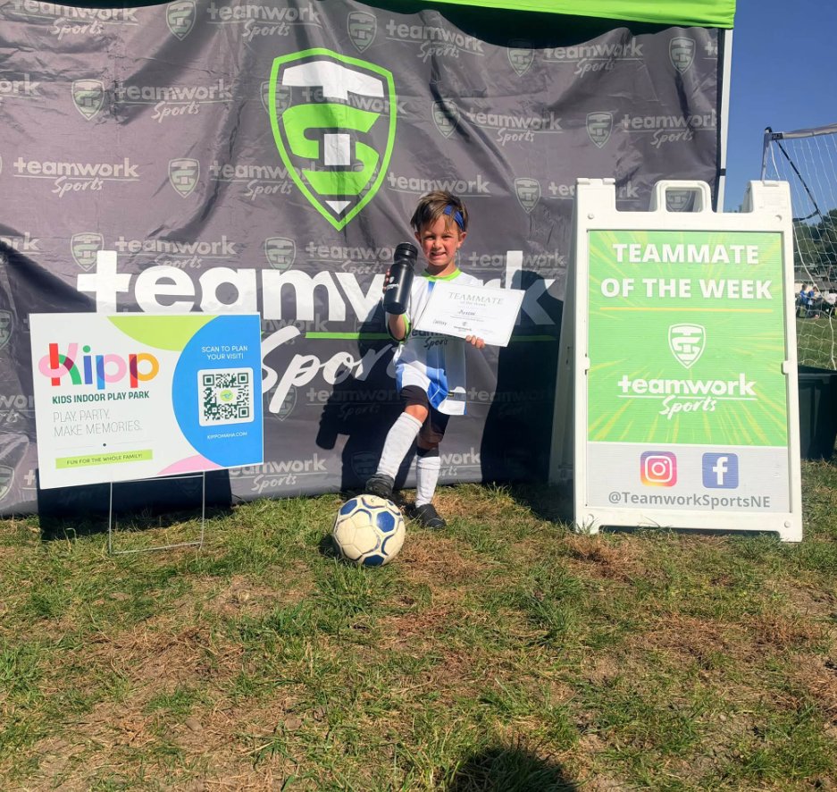 A young soccer player holding his Teammate of the Week certificate and water bottle