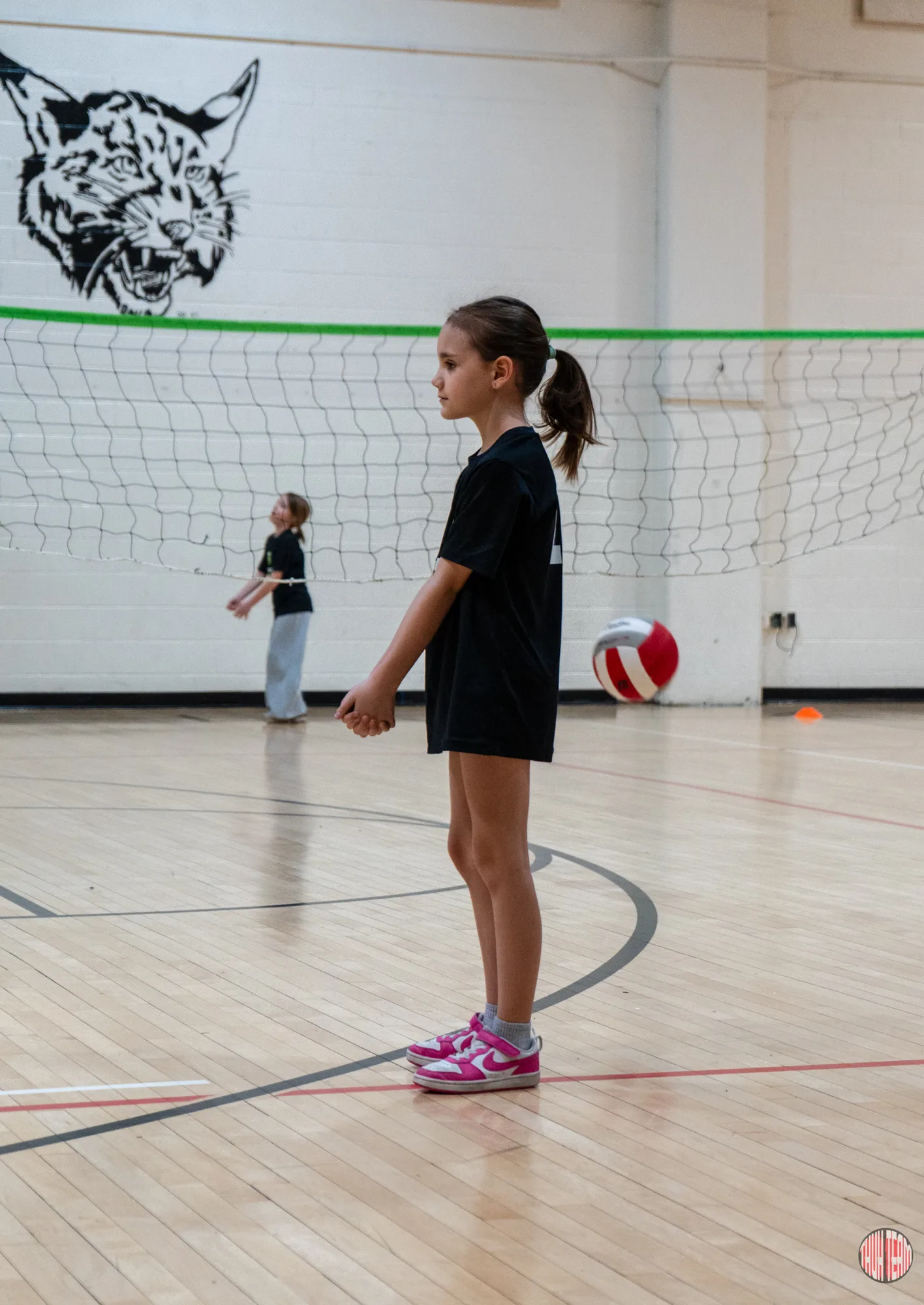 Girl in a Teamwork shirt waiting for a serve at the volleyball net