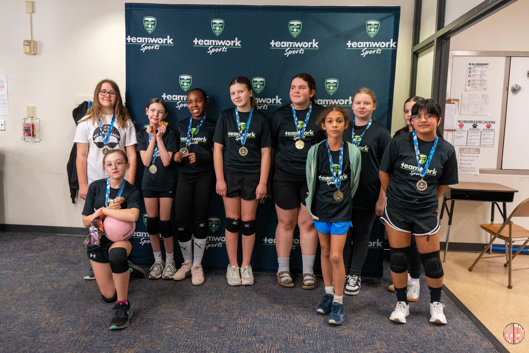 A volleyball team posing with their medals
